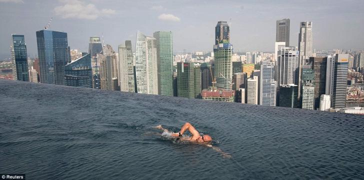 Don't look down: A guest swims in the infinity pool of the Skypark that tops the Marina Bay Sands hotel towers - 55 stories over the city of Singapore yesterday